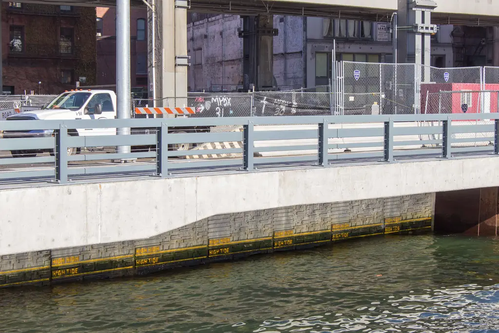 Newly built concrete seawall and waterfront railing along an urban shoreline